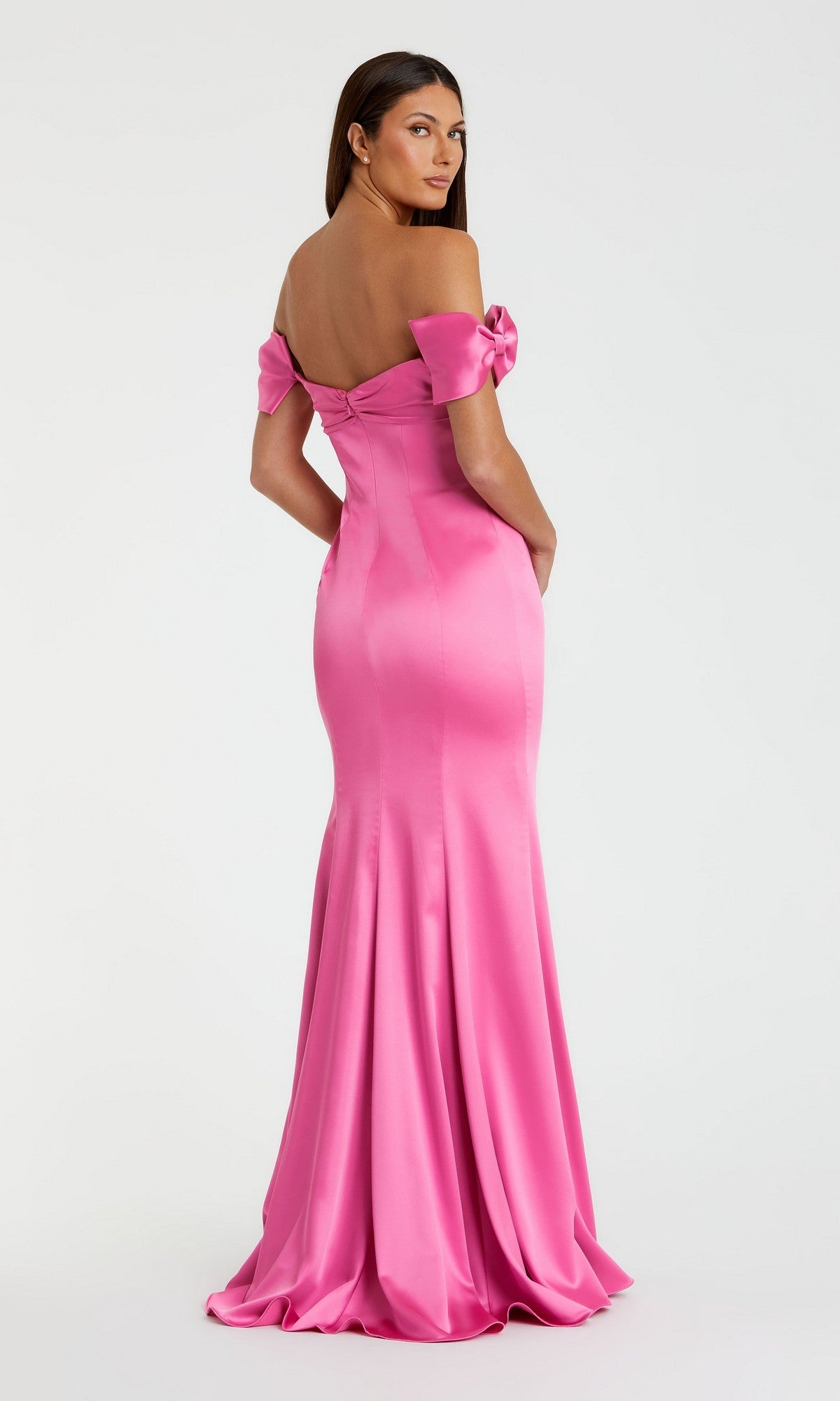 A woman models the Long Formal Dress: Mac Duggal 68875—a floor-length, off-the-shoulder fitted pink satin trumpet gown—posing with her back to the camera against a plain light background.